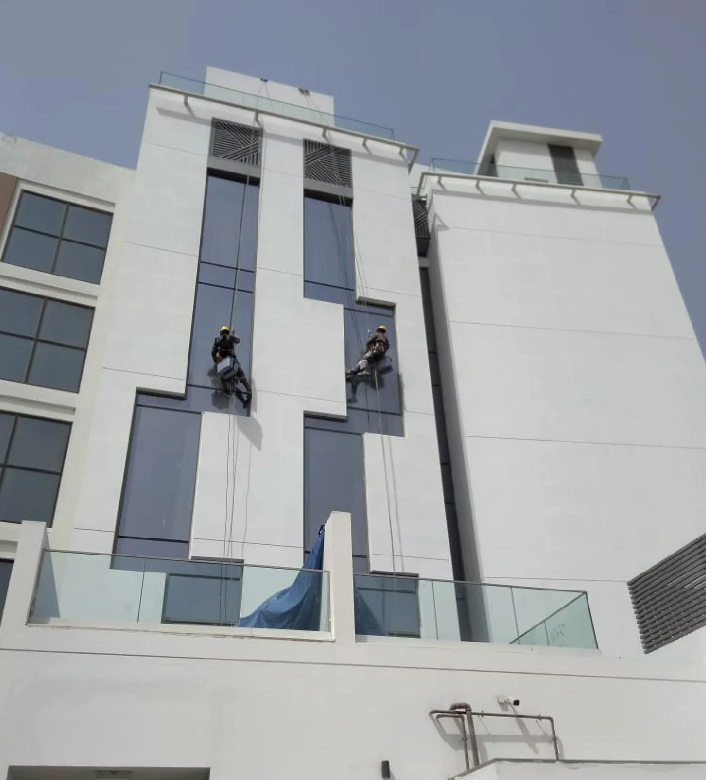 Rope-access technicians carrying out facade repair and painting works on a high-rise elevation.