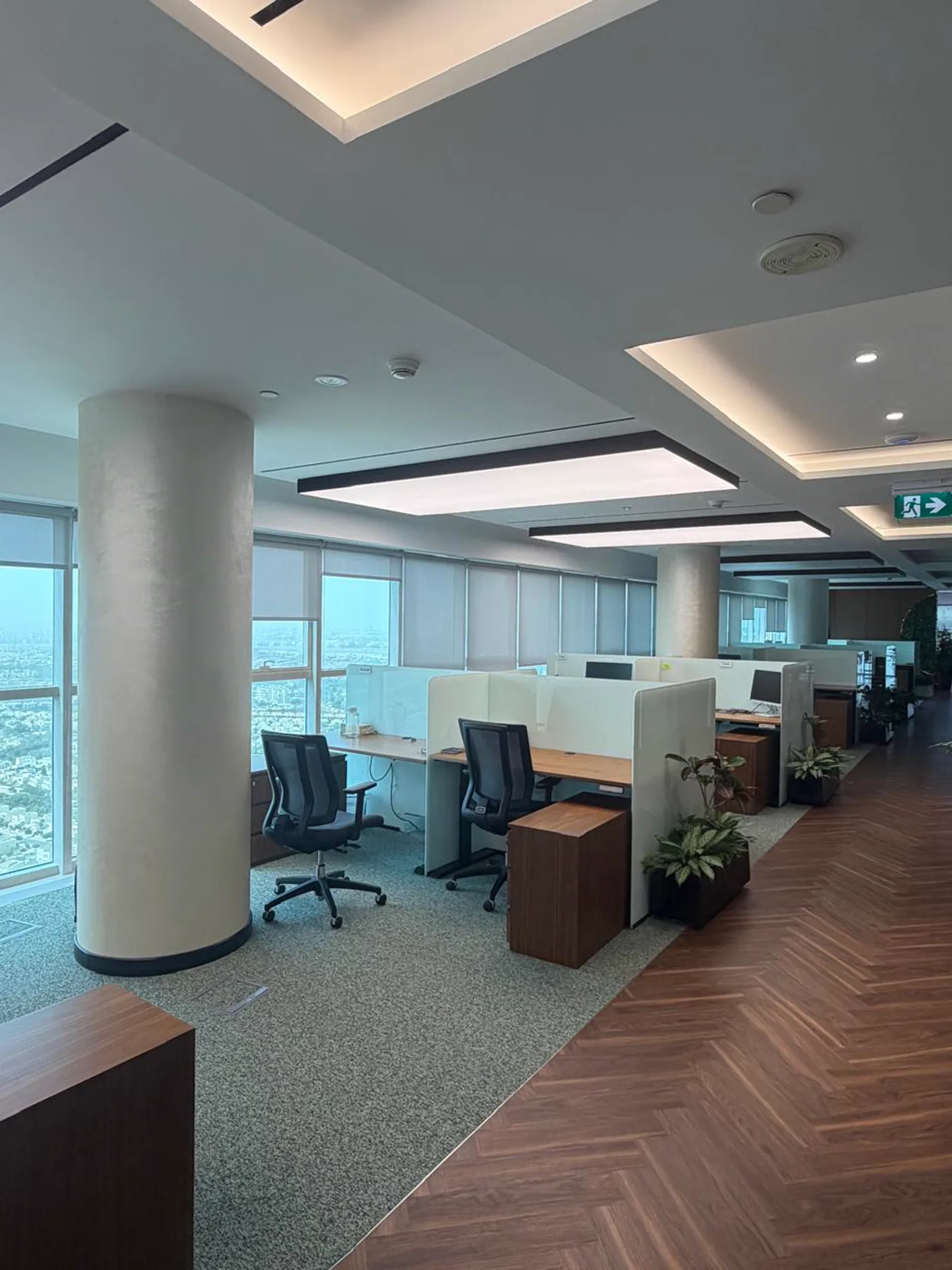 Open-plan workspace with acoustic screen workstations and floor-to-ceiling windows overlooking Dubai