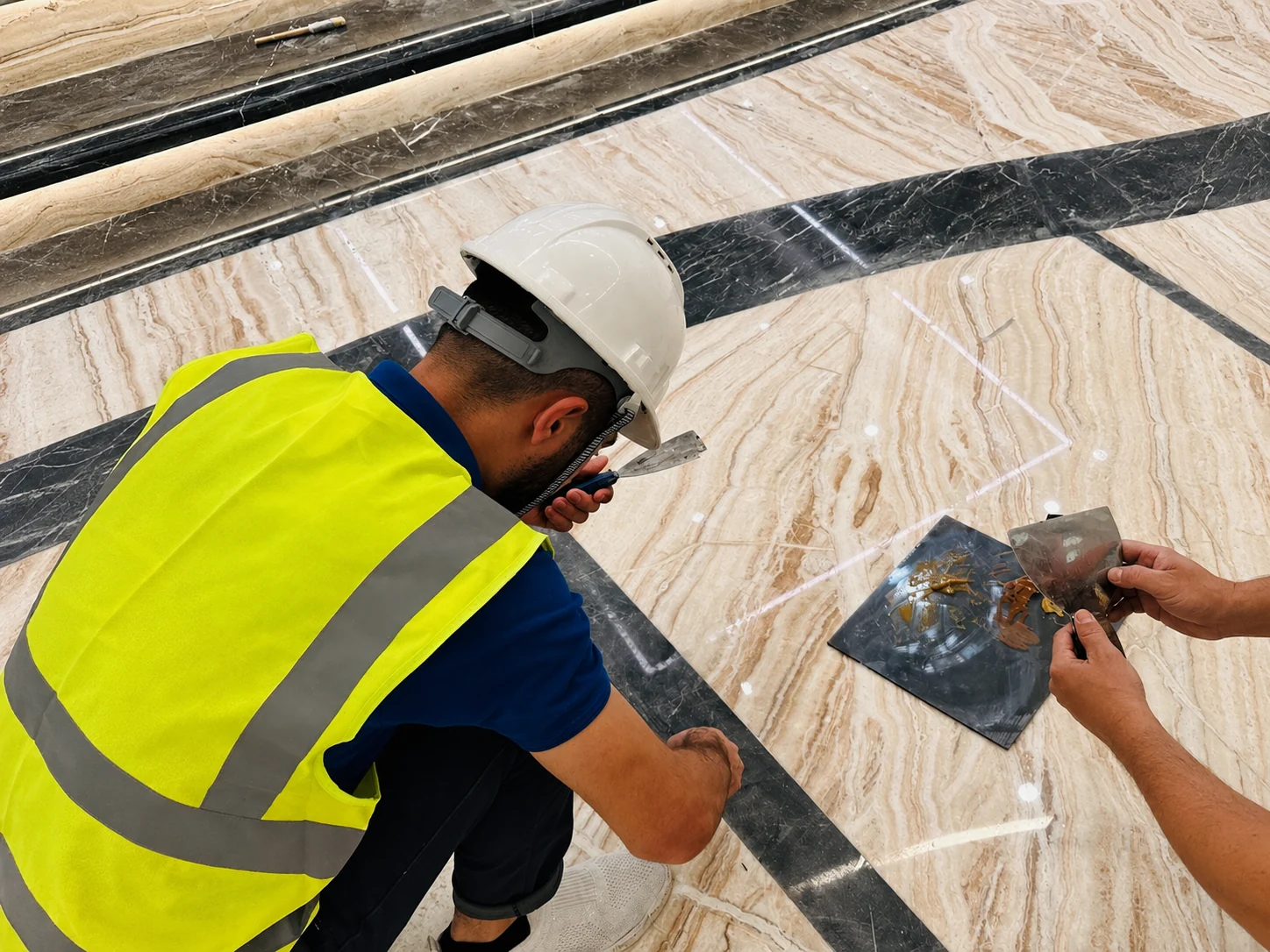 QMTS technician setting out and detailing a marble inlay border during floor installation.