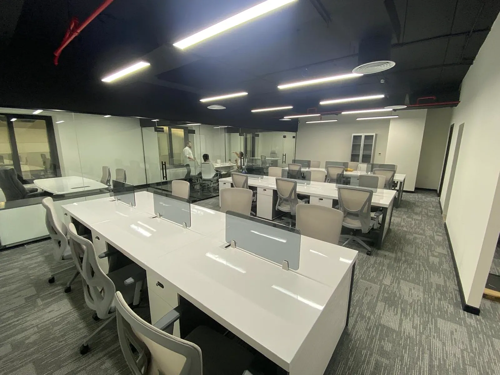 Completed MOODA Real Estate open-plan office with white workstations, frameless glass offices and linear ceiling lighting