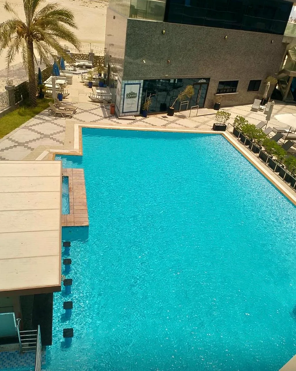 Elevated view of the pool showing coping, sun-deck tiling, planters and beachfront terrace at Park Regis by Prince Hotel