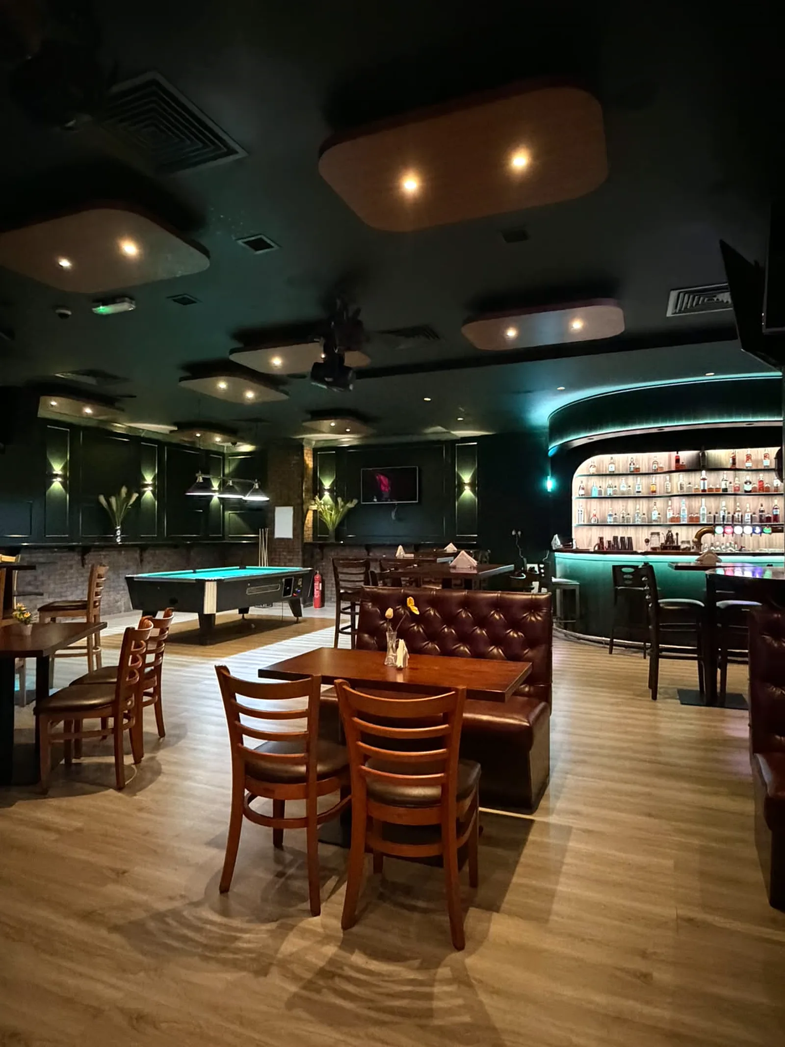 Dining and pool table area at Retox Bar with tufted leather banquettes, acoustic ceiling rafts and feature wall lighting